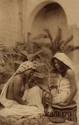 Harem meninas fumando um cachimbo de água, de um cartão postal do início do século XX (foto sépia)