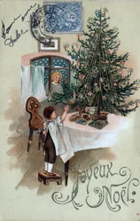 Cartão de Natal: uma criança em frente a uma árvore de Natal posa sobre uma mesa, observada por um anjo na janela - Cartão postal datado de 1905