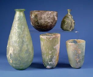 No sentido horário a partir da esquerda: frasco de vidro verde em forma de pêra, Sasanian, século 3-7 d.C.; taça de vidro âmbar pálido, Sasanian, século 5-6 d.C.; frasco de vidro verde islâmico em forma de pêra, século 8-12 d.C.; dois copos de vidro verde 