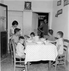 Grande família reunida à mesa na sala de jantar da casa de campo. 1960s