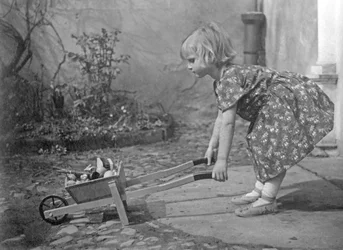 Uma menina a brincar com um carrinho de mão. Fotografia por volta de 1931
