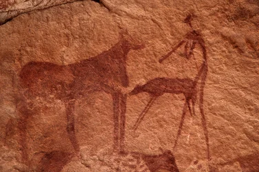 Arte rupestre, Pré-história: Pintura rupestre de uma vaca, bezerro e personagem (arqueiro) num abrigo ornamentado, no maciço de Uweinat, Egipto. (Período de 8000 a 3000 anos a.C.). Fotografia