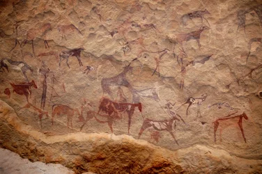 Arte rupestre, Pré-história: Pintura rupestre de um grupo de gado e personagens policromáticos (pastores e arqueiros) num abrigo ornamentado, no maciço de Uweinat, Sudão. Período de 8000 a 3000 anos antes de Cristo. Fotografia