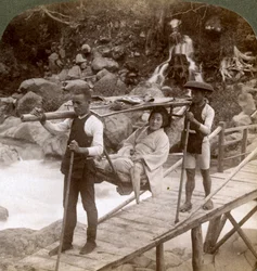Mulher japonesa em uma cadeira de montanha yamakago atravessando o torrencial rio Daiya perto de Nikko, Japão,