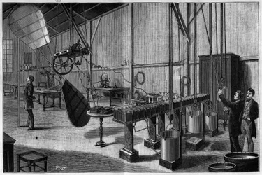 Oficina aerostática de Tissandier freres: Vista geral de uma hélice com duas paletes helicoidais operadas por uma máquina elétrica Siemens dynamo e uma bateria de baterias de bicromate potássio leve. Gravura de 1883. em "La Nature. Revisão das ciências e d