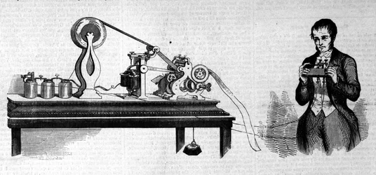O inventor americano Samuel Finley Breese Morse (1791- 1872) representa ao lado do seu telégrafo. Gravura do século XIX