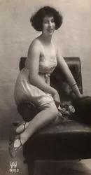 Uma jovem mulher posando com o seu saiote, sentada numa poltrona