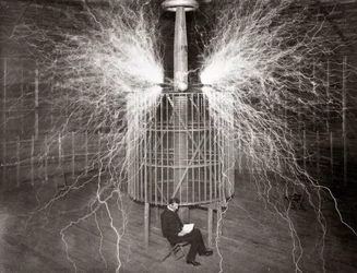 Nikola Tesla sentado no seu laboratório em Colorado Springs com o seu "Transmissor de Ampliação"