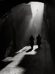 Dois homens caminham numa pequena rua típica de Florença