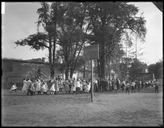 Meninos e meninas brincando de cabo-o-guerra em um playground não identificado, c.1910