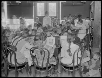 Crianças que leem na sala de leitura de um ramo não identificado da biblioteca pública da cidade de Queens, c.1910.