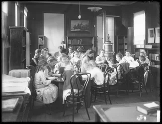 Crianças lendo na sala de leitura de um ramo não identificado da Biblioteca Pública de Queens Borough, c.1910