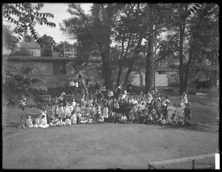 Grande grupo de crianças reunidas para um retrato de grupo em um playground não identificado, c.1910