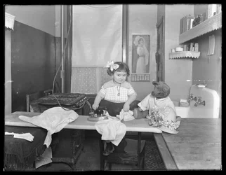 Menina não identificada, demonstrando o uso de um ferro elétrico, c.1913-14