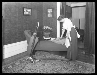 Mulher não identificada demonstrando o uso do acessório de estofamento Apex aspirador, c.1913-14