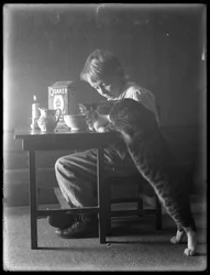 William Gray Hassler e Reddy o gato, comendo cereal de arroz inchado Quaker, c.1912
