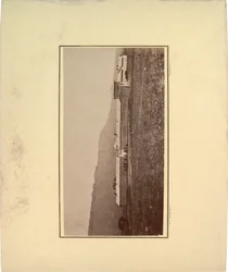 Vista de uma paliçada com vários homens reunidos no portão de entrada, 1871 (foto sépia)