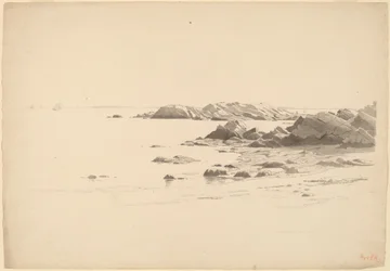 Praia rochosa com barcos distantes