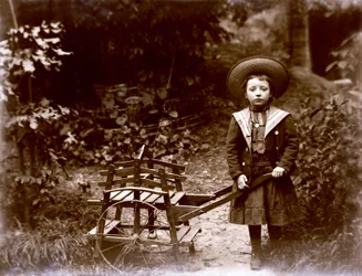 Menina com carrinho em um jardim, início do século XX (foto p/b)