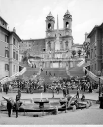 Vista da Piazza di Spagna: em primeiro plano encontra-se a Fontana della Barcaccia, além da escadaria um obelisco e a Igreja de Trinità dei Monti.